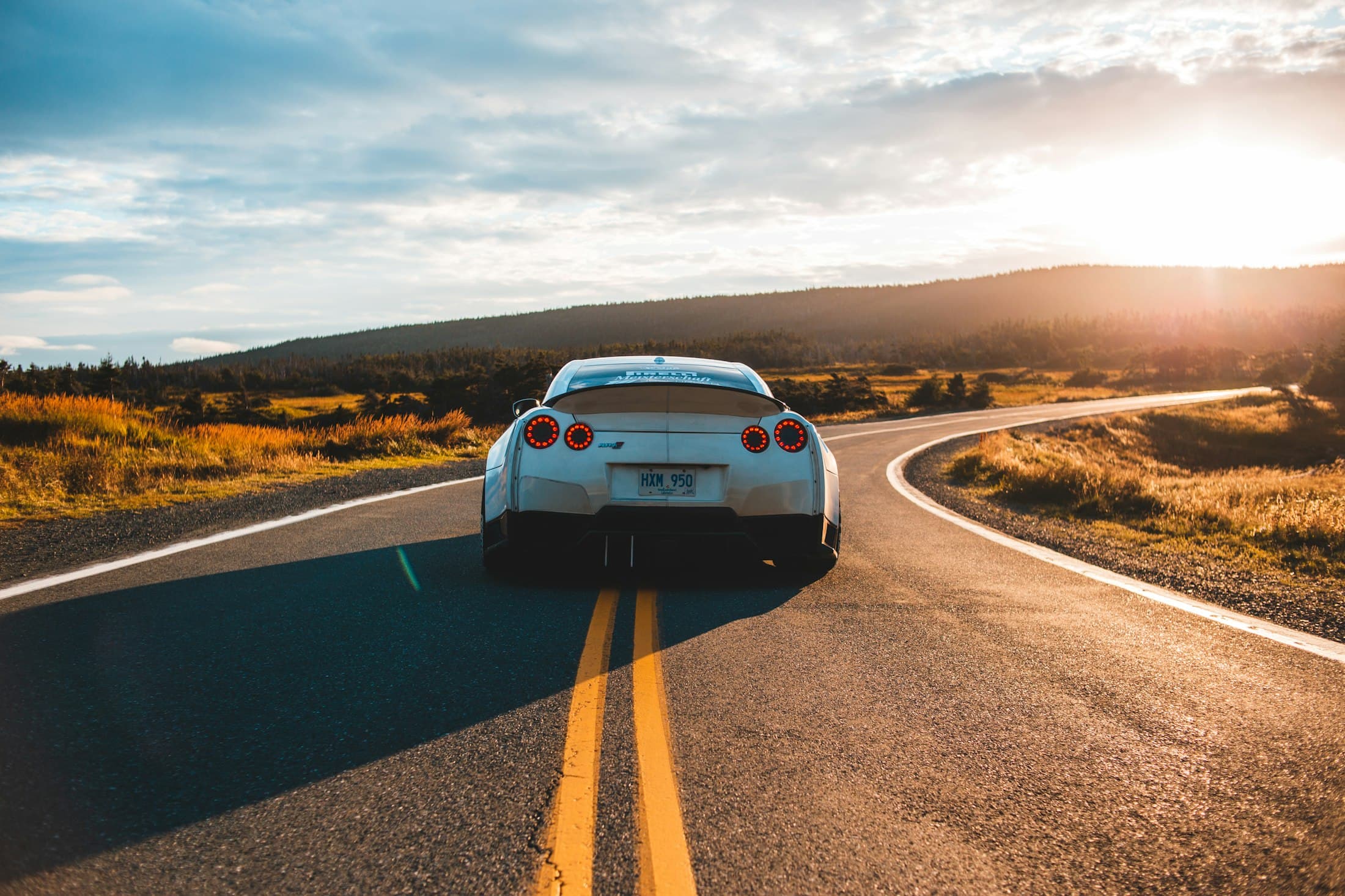 Voiture de sport sur une route sinueuse en fin de journée