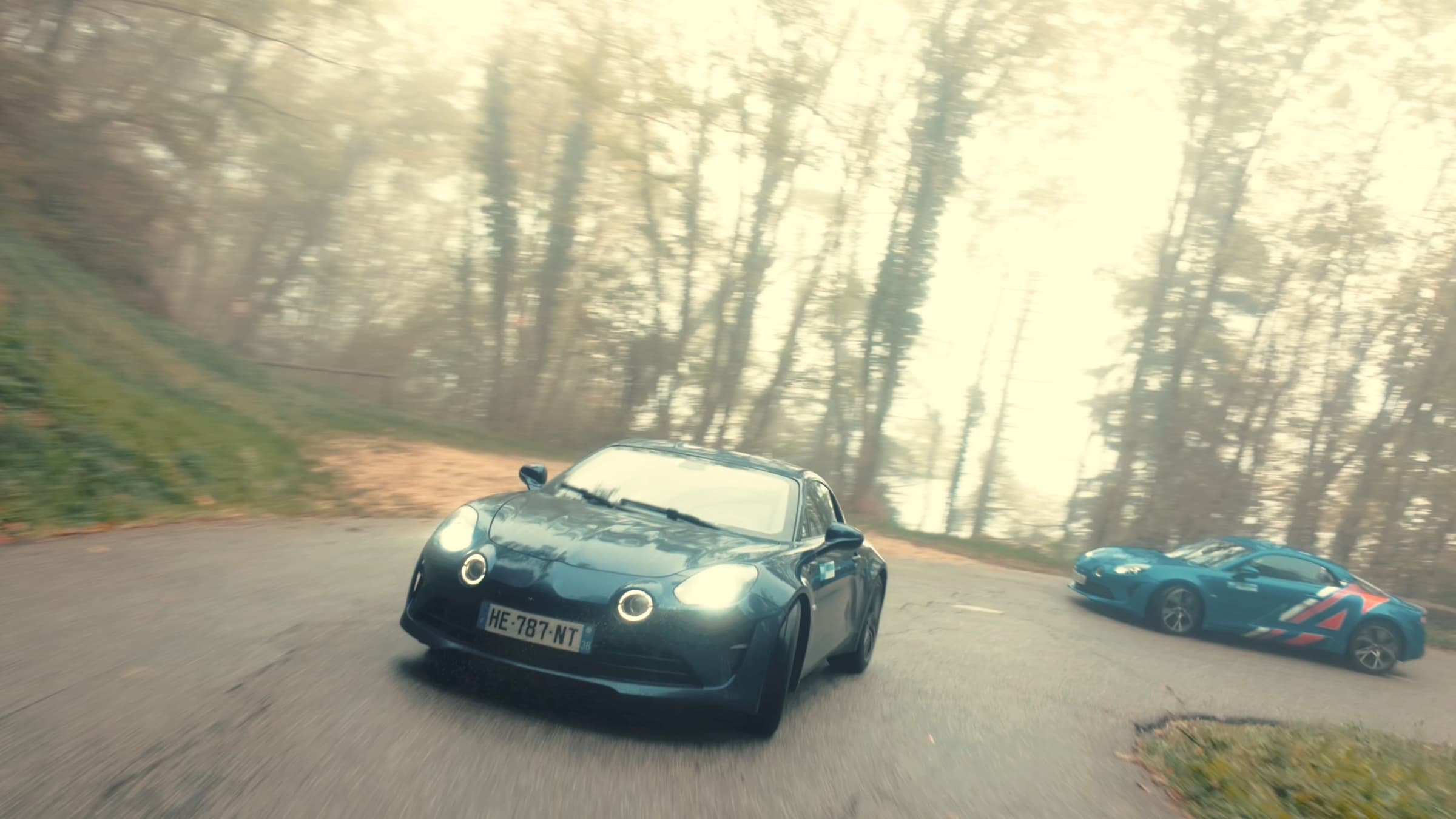 Deux Alpine A110 dans une épingle sous la brume